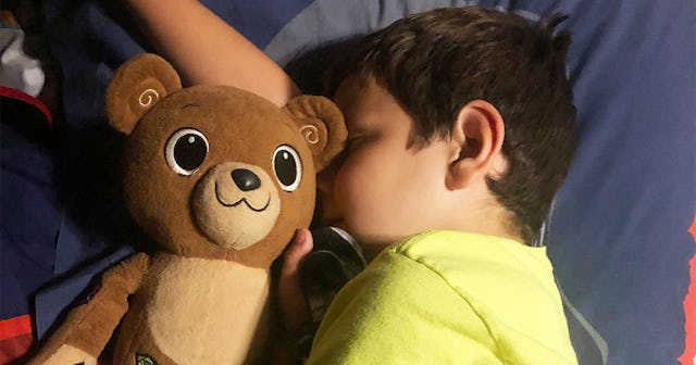 A boy with Type 1 Diabetes laying in bed with his teddy bear