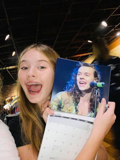 A teenage girl posing with Harry Styles calendar