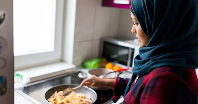 A woman wearing a hijab preparing a meal in a kitchen