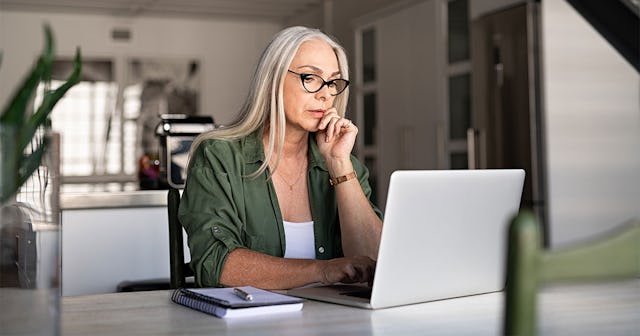 A woman who lost her daughter to estrangement, sitting and looking at a laptop.