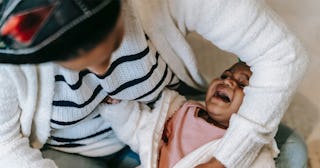 An overwhelmed mother getting her crying kid dressed