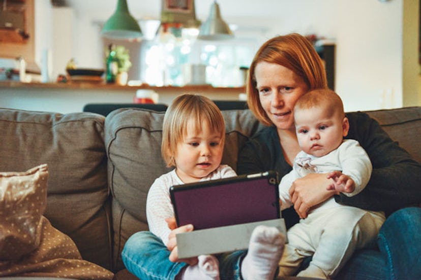A woman with two kids showing them something on a tablet