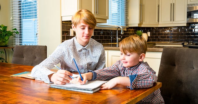 An older brother showing homework to his younger brother during the pandemic
