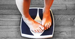 A person stepping on a scale, and covering the numbers it shows with feet