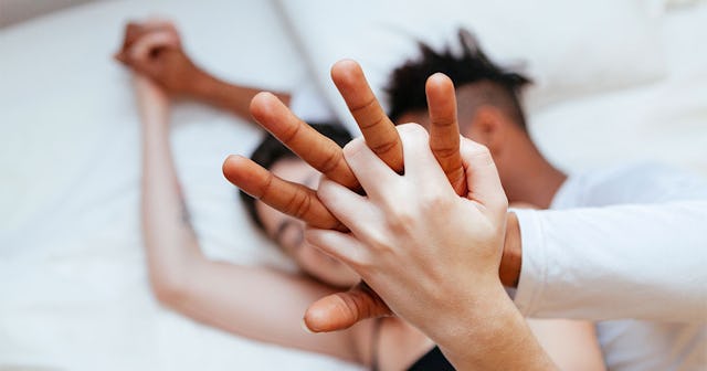 A couple laying in bed holding hands.