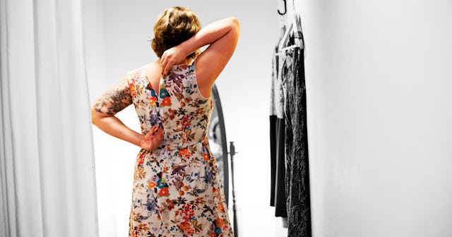 A woman trying on a floral dress in a changing room