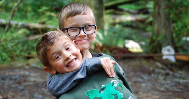 Christina Moog's sons posing and smiling while hugging in a forest