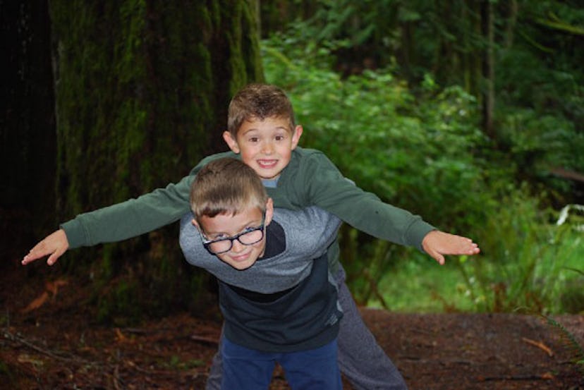 Christina Moog's son holding his brother on his back in the woods while smiling