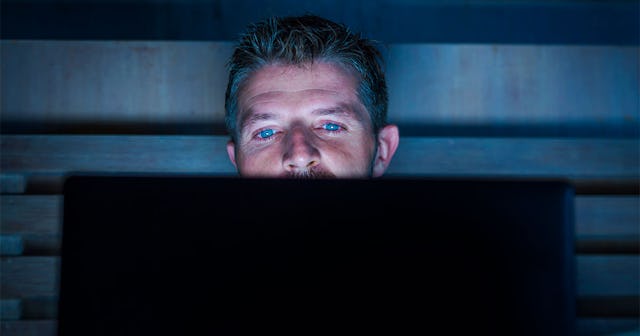 Man watching porn videos on his laptop in a dark room
