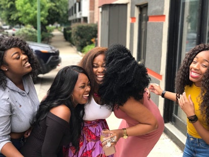 A group of five smiling black women who champion and support each other