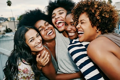 A group of five smiling black women who champion and support each other