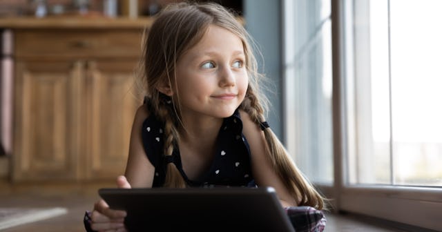 A girl with braids lying on the floor with a tablet
