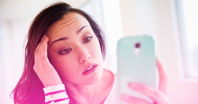 A woman holding her head while on the phone with annoyed look on her face