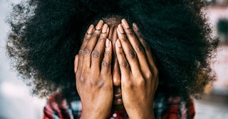  Curly-haired woman covering her face with her hands 
