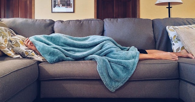 woman on couch covered in blue blanket