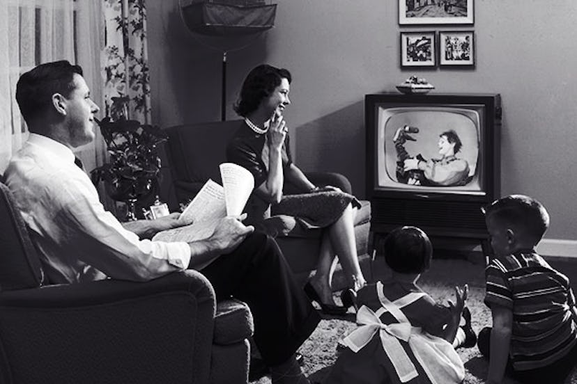 What looks like a perfect 50s family, parents and two kids watching TV in black and white