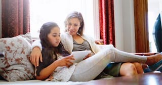 Mother and daughter sitting on the couch reading the book "The care and Keeping of You"