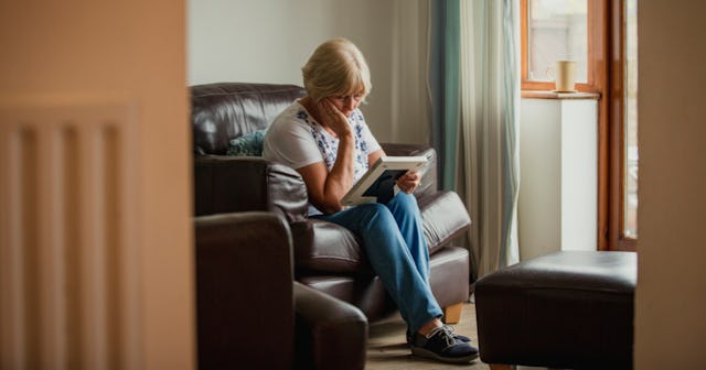 A mother sitting on a couch looking at a photo of her estranged daughter