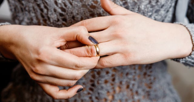 A woman with a black manicure taking off her wedding ring