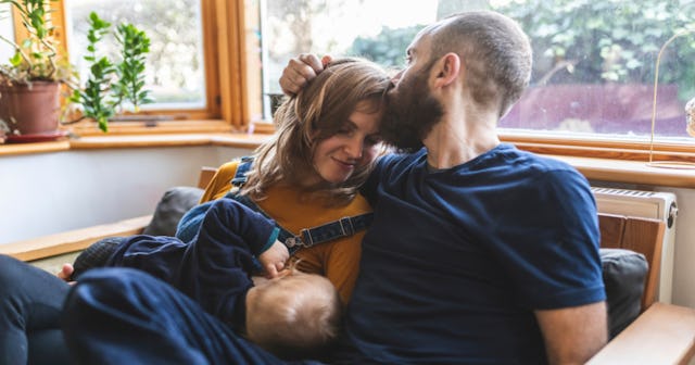 Husband kissing wife's forehead while she is breastfeeding