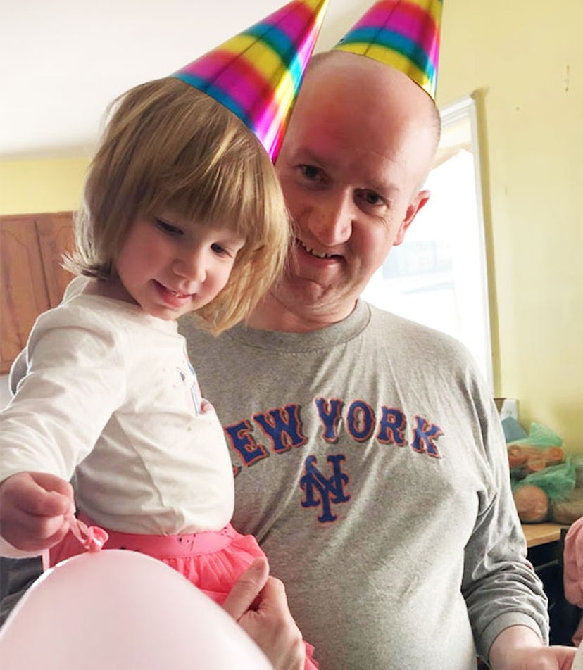 A dad holding his daughter while their wearing party hats for a birthday celebration