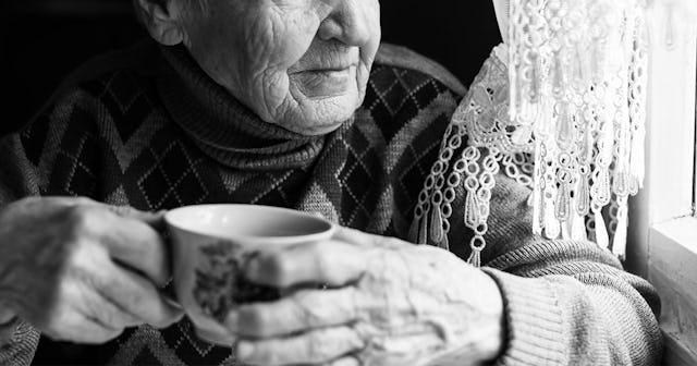 A grandmother drinking coffee and looking through the window