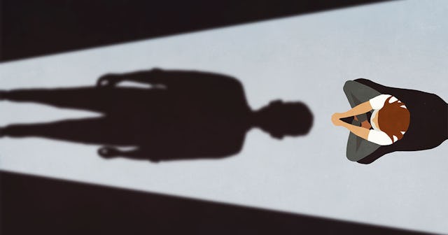 Scared child curled up sitting in the corner, while his grandfather's big shadow is over him