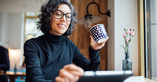 A woman is sitting, drinking coffee, and looking at a tablet in front of her, and she has discovered...