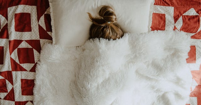 older child in bed with blanket pulled over head