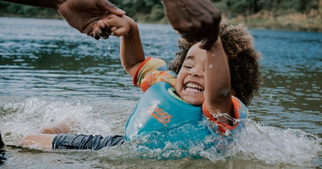 how to teach kids to swim, child wearing float vest in water