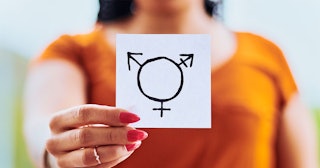 A lady holding a paper with an intersex symbol drawn on it