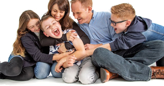 A young boy, afflicted by vanishing white matter disease, smiling as his family envelops him in warm...