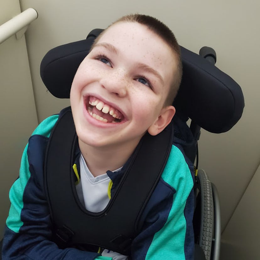 A boy with a vanishing white matter disease sitting in his wheelchair while smiling 