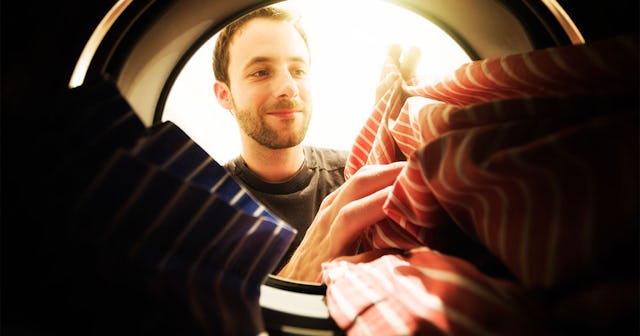 A man doing the laundry and putting two striped shirts into the washing machine
