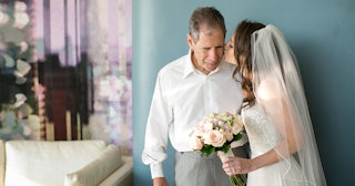 A bride in a white dress and a veil holding a bouquet while kissing her father, who has Alzheimer's ...