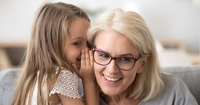 A girl leaning and whispering something to her older mom