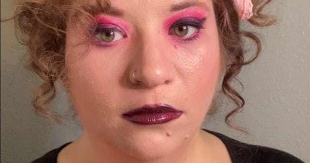 Woman with curly ginger hair wearing bright pink eyeshadow and a bold burgundy lipstick