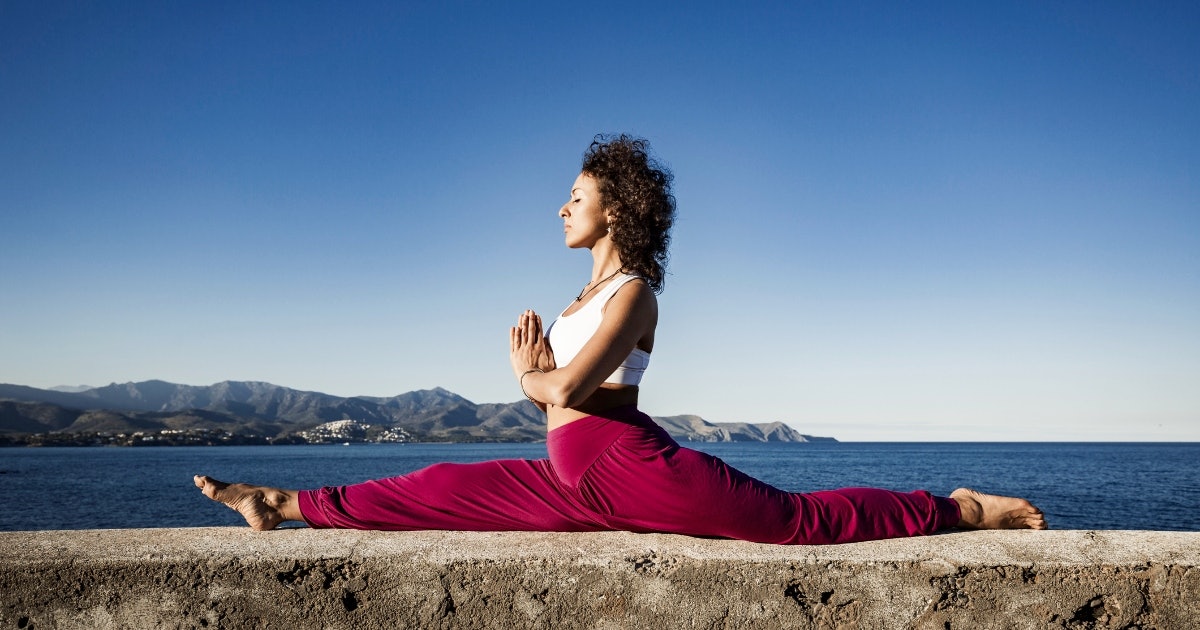 Woman doing boat yoga pose on the beach