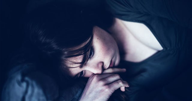 A worried mother laying on a bed wearing black shirt