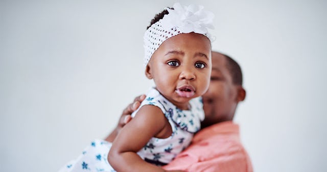 A father in a pink shirt who had major anxiety about having a daughter holding his girl while smilin...
