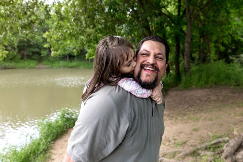 A father who had major anxiety about having a daughter with a beard and gray shirt is smiling while ...