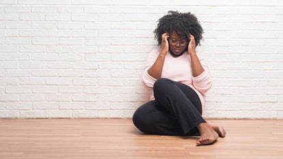 A black mom sitting on the floor depressed because of systemic injustice over black lives