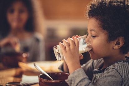 A kid drinking milk out of a glass.