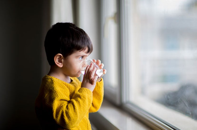 A kid drinking water out of a glass.