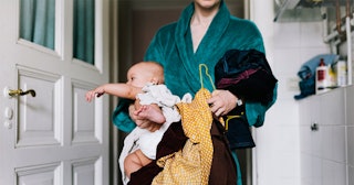 Busy mom carrying her baby and clothes at the same time while wearing a green bathrobe