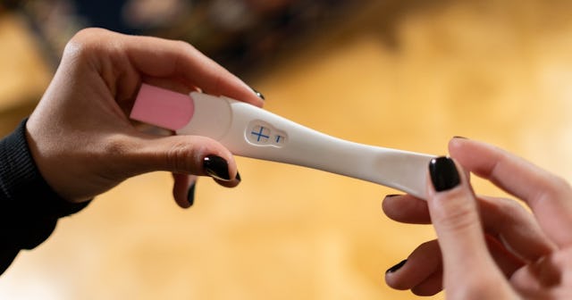 pregnancy test calculator, woman holding pregnancy test