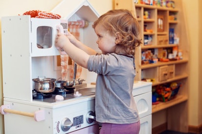 A little girl playing with a kitchen toy set 