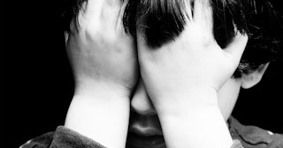 Abused boy desperately covering his face with his hands because he has an abusive mom
