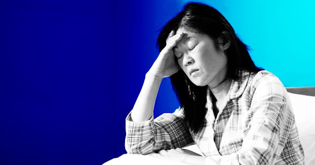 A woman sitting down holding her head with the hand looking worried