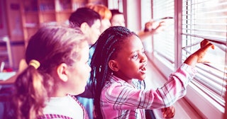 A group of children standing in front of a window and looking